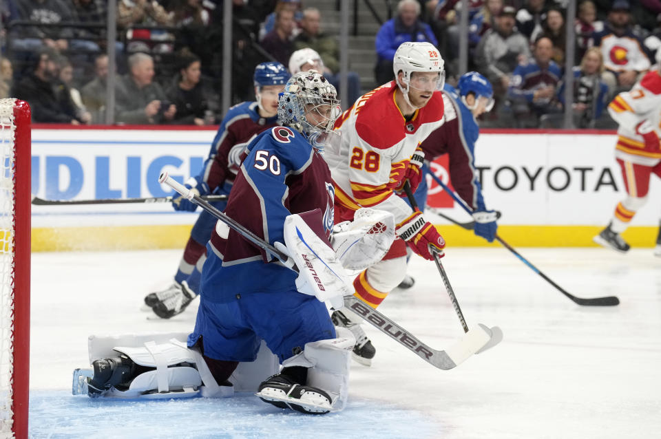 Calgary Flames center Elias Lindholm (28) looks for a pass in front of the net as Colorado Avalanche goaltender Ivan Prosvetov (50) defends in the second period of an NHL hockey game Saturday, Nov. 25, 2023, in Denver. (AP Photo/David Zalubowski)