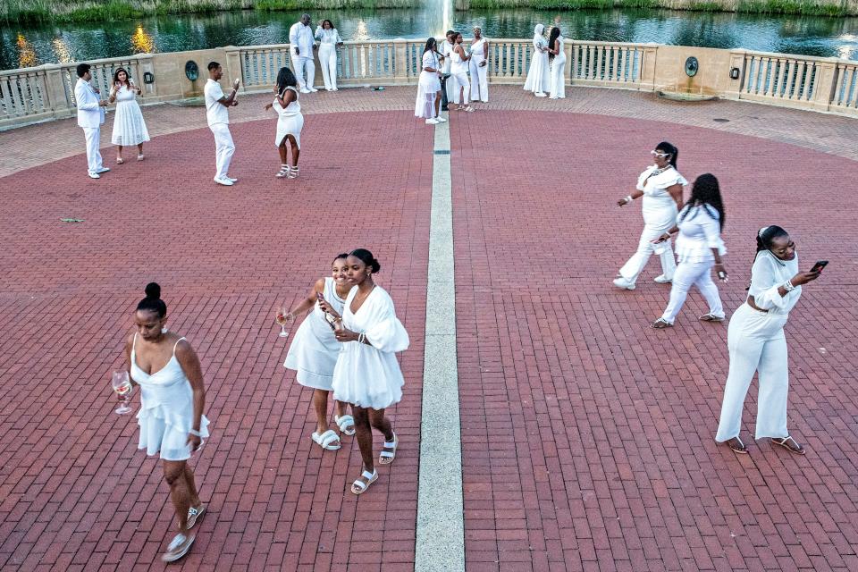 Le Dinner En Blanc participants enjoy the gazebo at the Cool Springs Reservoir in Wilmington, Saturday, Sept. 17, 2022. Guests, who found out about the location of the dinner shortly before the event, wore all-white, set up elaborate dinner settings and brought their own food.