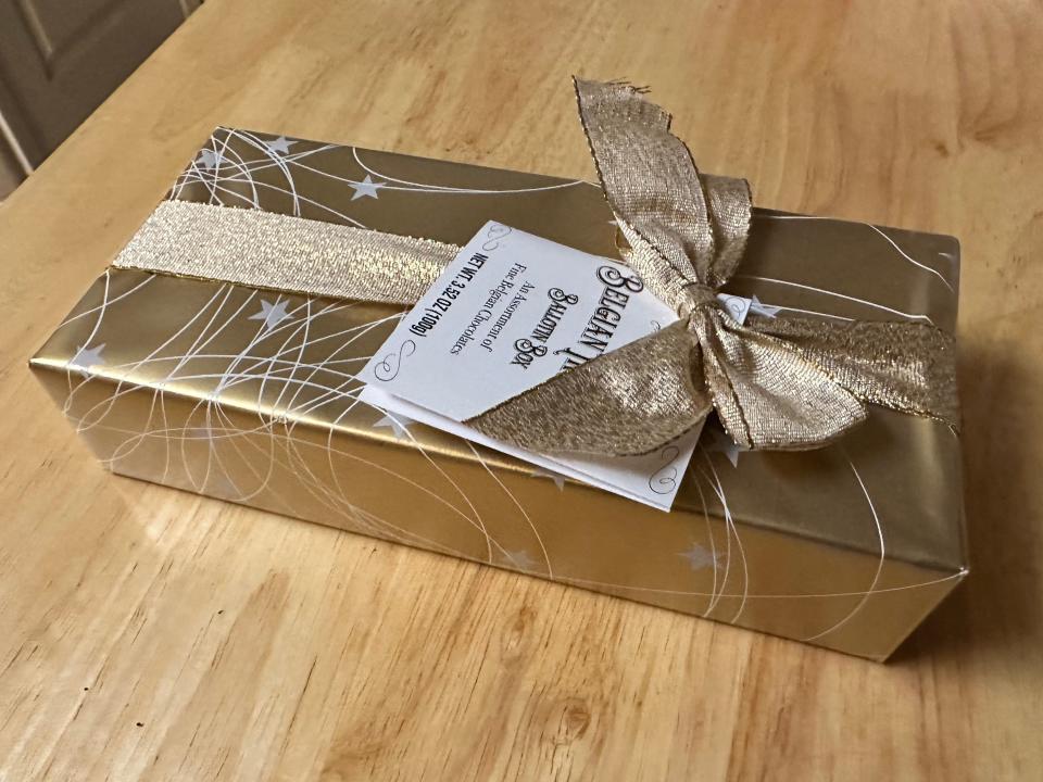 Gold box with ribbon of belgian truffles from trader joe's on wood table