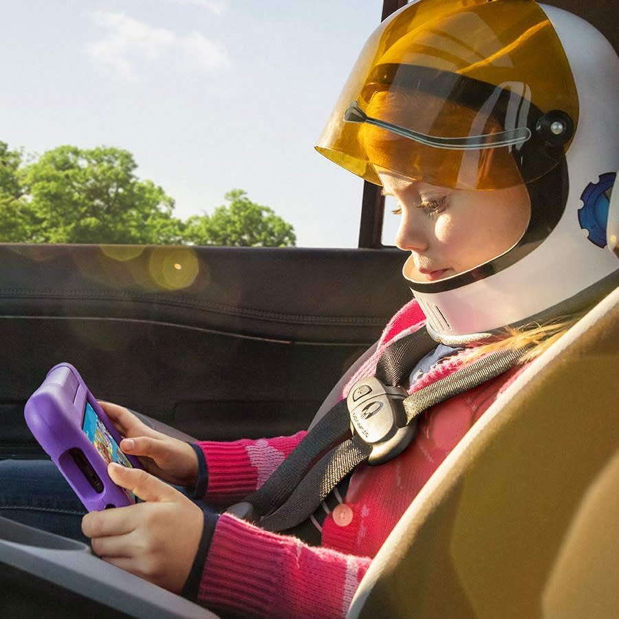 kid in car wearing a helmet and watching a purple tablet