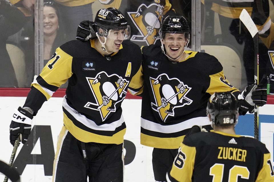 Pittsburgh Penguins' Rickard Rakell (67) celebrates his second of two goals during the first period, with Evgeni Malkin and Jason Zucker during an NHL hockey game in Pittsburgh, Sunday, April 2, 2023. (AP Photo/Gene J. Puskar)