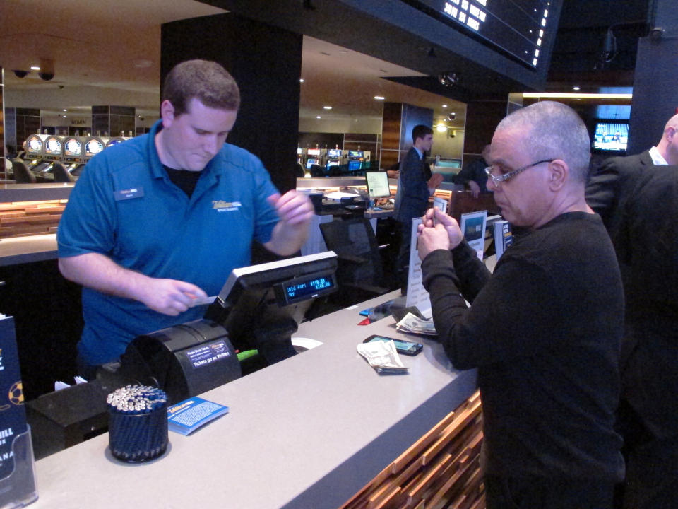 File- A gambler prepares to hand over cash at the sportsbook betting window inside the Tropicana casino in Atlantic City N.J. on March 8, 2019. On Sept. 14, 2020, New Jersey gambling regulators announced that New Jersey set a new national record for the amount wagered on sports in a single month in the U.S. with nearly $668 million bets on games. (AP Photo/Wayne Parry, File)