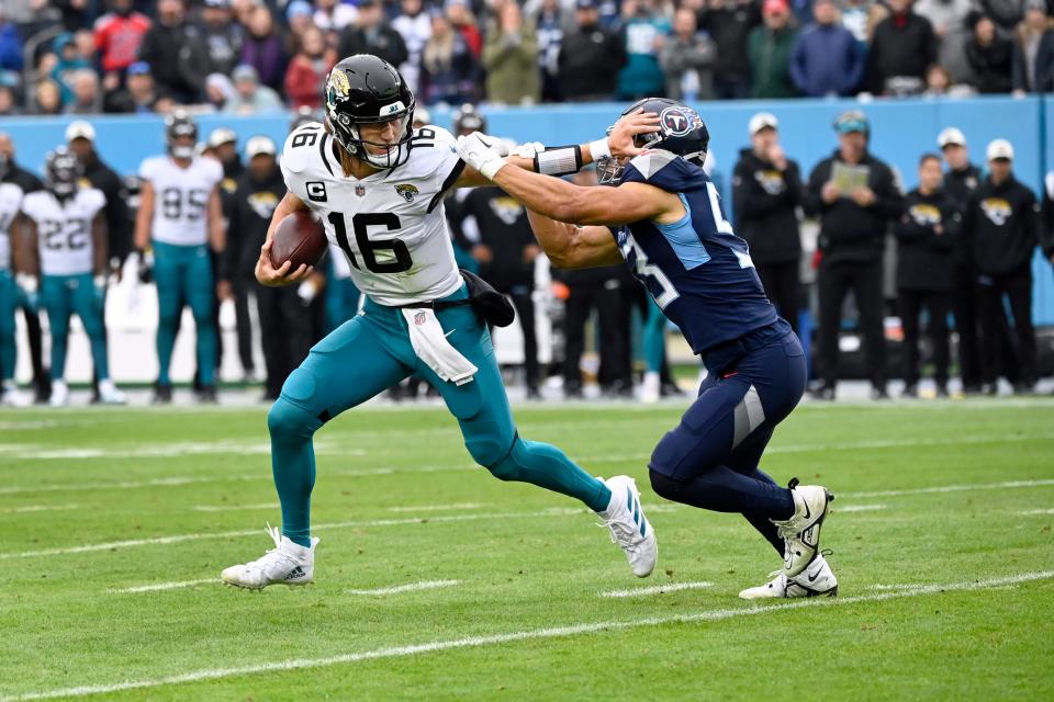 Jaguars quarterback Trevor Lawrence stiff-arms Titans linebacker Dylan Cole during Sunday's game at Tennessee, on his way to a 1-yard TD run.