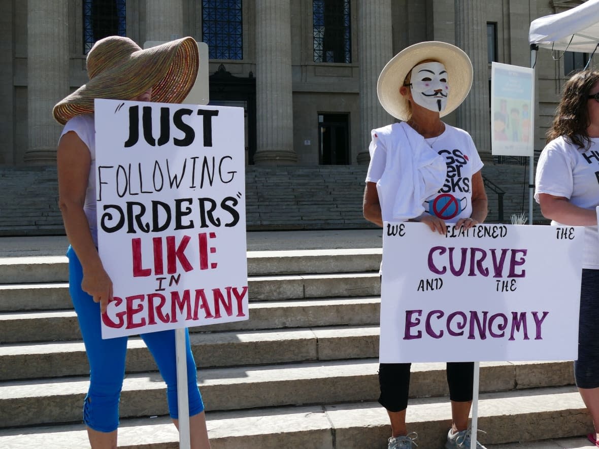 Protesters are seen holding masks at an anti-mask rally at the Manitoba legislature in Winnipeg in August 2020, including one sign that equates public health orders with Nazism. Comparisons to the Nazi era are becoming a common sight at demonstrations against public health measures aimed at containing the spread of COVID-19. (Jaison Empson/CBC - image credit)