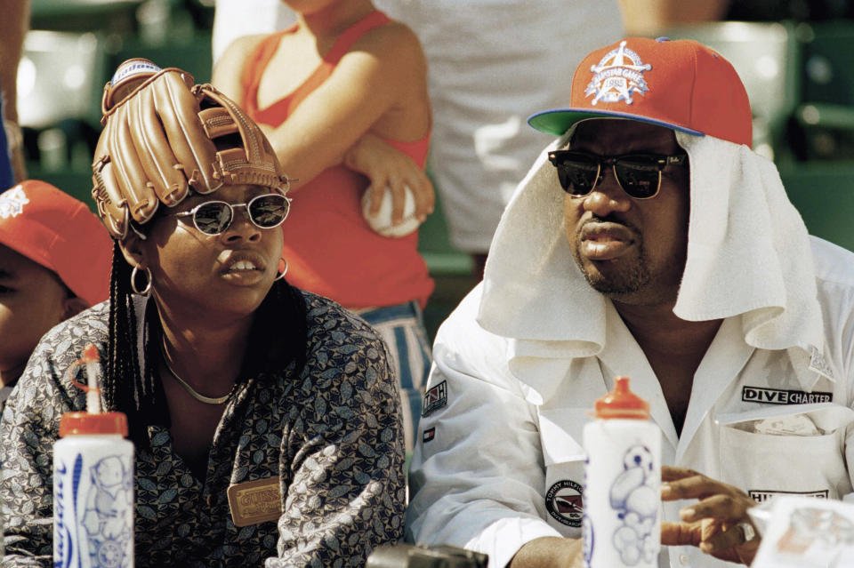 FILE - Tiffany Layton, left, and Gregory Taylor, right, protect themselves from the heat before the All-Star baseball game at the Ballpark in Arlington in Arlington, Texas, July 11, 1995. Major League Baseball is playing its All-Star Game in Arlington for the first time since 1995, when the Rangers played outside in the stifling heat. This year's game will be played Tuesday, July 16, 2024, in their stadium with a retractable roof that opened in 2020. (AP Photo/Eric Gay, File)