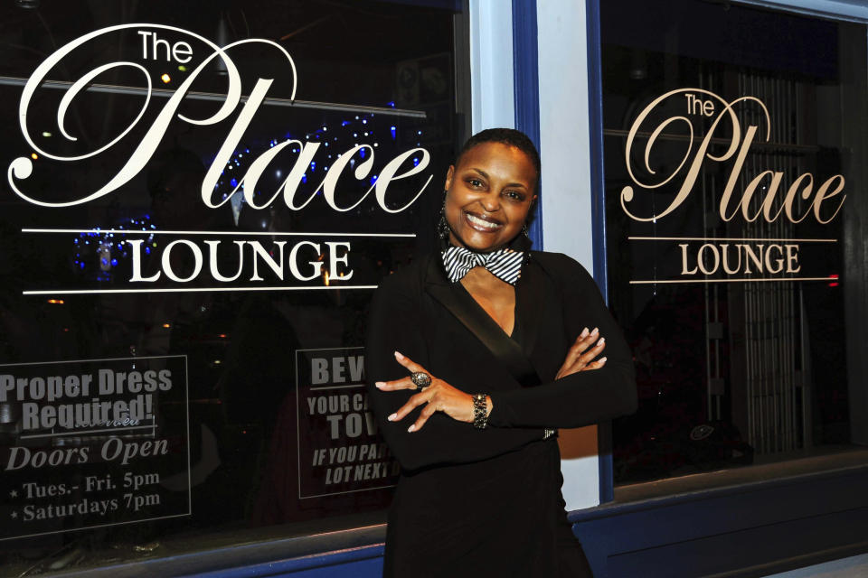 In this photo released by Kevin Brown/Browns Photography, Ann Winder, owner of The Place Lounge, stands in front of the over-30 bar featuring jazz, R&B and house music in Baltimore in January 2023. The longtime bar owner expects a boost in traffic during this week’s CIAA basketball tournament at CFG Arena, which is just five blocks south of The Place. (Kevin Brown/Browns Photography via AP)