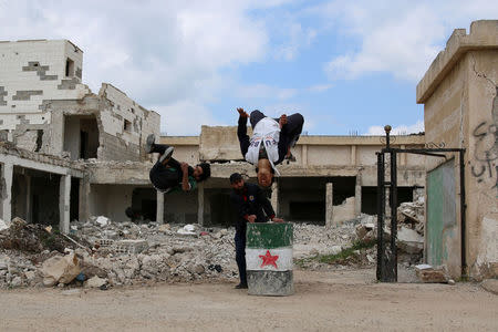 Parkour coach Ibrahim al-Kadiri (L), 19, and Muhannad al-Kadiri, 18, demonstrate their parkour skills over a bin painted with an opposition flag in the rebel-held city of Inkhil, west of Deraa, Syria, April 7, 2017. "Parkour makes me a mythical man. It gets us out of the atmosphere of war and makes us forget some of our pain and sorrows, for when i jump from a high place I feel free and i enjoy the fun," Muhammad says. REUTERS/Alaa Al-Faqir