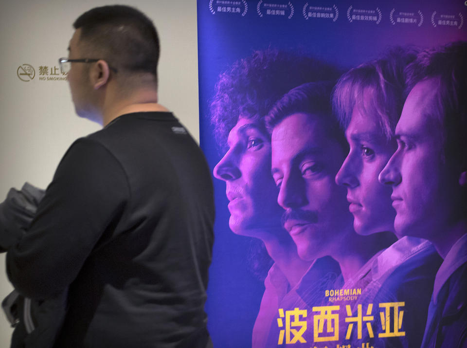 A customer walks past a movie poster for the film "Bohemian Rhapsody" at a movie theater in Beijing, Wednesday, March 27, 2019. Moviegoers in China say the version of the "Bohemian Rhapsody" shown in Chinese theaters erases mentions of Freddie Mercury's sexuality. The biopic on the lead singer of the British rock band Queen omitted a same-sex kiss and lacked scenes in which Mercury reveals he's not straight and has AIDS. (AP Photo/Mark Schiefelbein)