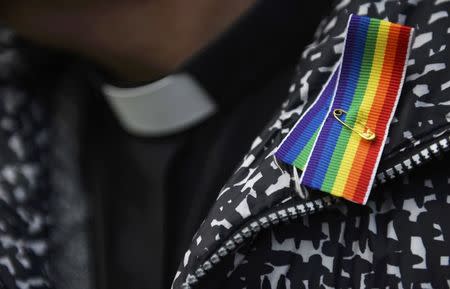 A priest wears a rainbow ribbon during a vigil against Anglican Homophobia, outside the General Synod of the Church of England in London, Britain, February 15, 2017. REUTERS/Hannah McKay