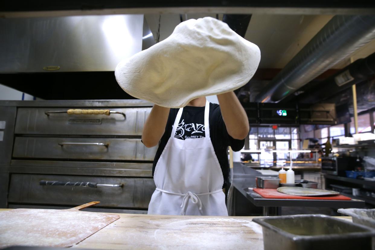 Jonathan Chavez tosses pizza dough Tuesday, March 26, 2024 at Graze Gourmet To Go in Iowa City, Iowa.