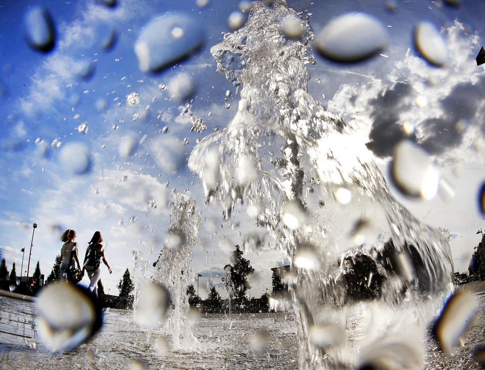 Two girls walk past a fountain on a square in Frankfurt