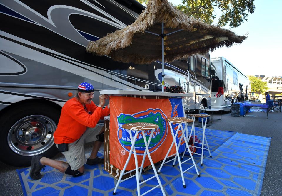 Lucian Lawley, the owner of Whitey's Fish Camp in Fleming Island, secures a Gator flag to his pop-up tiki bar in RV City Tuesday morning. He and his RV arrived Thursday and were seventh in a line waiting to get in. He has taken breaks though to report to his restaurant for work.