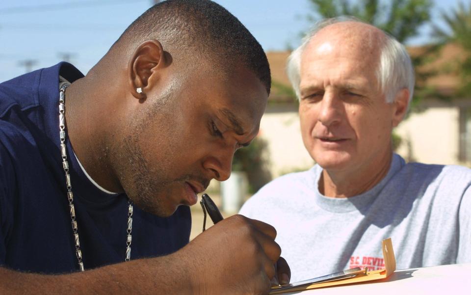 Levi Jones signs autographs a picture for Jay Denton, his former high school football coach, in Eloy before Jones was drafted by the Cincinnati Bengals in the first round of the NFL draft Saturday. Jones was the 10th overall pick in the 2002 draft.