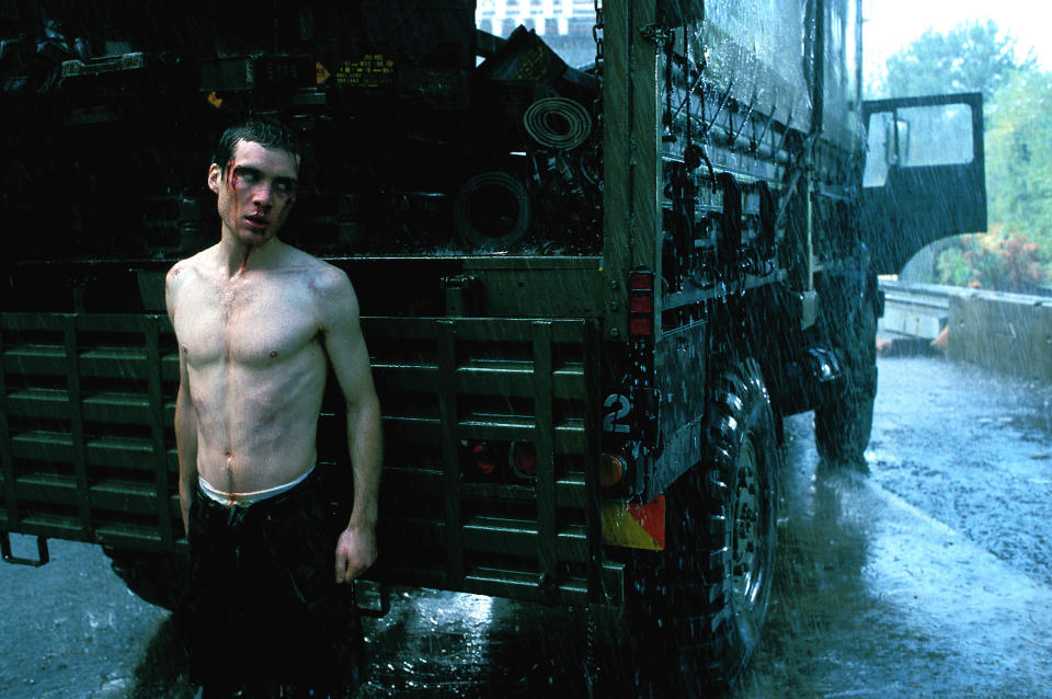 Cillian Murphy with a bloodied face standing behind a truck.