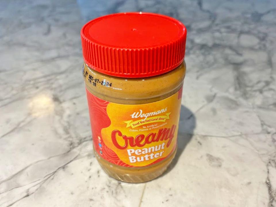 A jar of peanut butter with a bright-orange and red label with a red lid