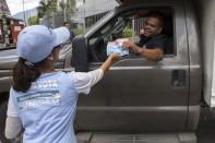 A driver receives a flyer from a supporter of MIN Unidad Party with information on how to vote in Caracas, November 3, 2015. REUTERS/Marco Bello