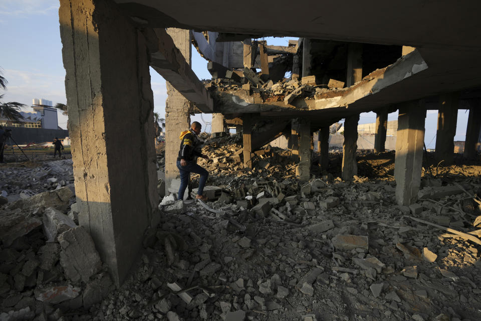 A young man walks through the rubble of a destroyed building hit by Israeli airstrikes in Gaza City, Monday, Feb. 13, 2023. Earlier on Monday, the Israeli military said aircraft bombed a Hamas rocket manufacturing site and military installations in the Gaza Strip after Palestinian militants launched four rockets into southern Israel overnight. (AP Photo/Adel Hana)