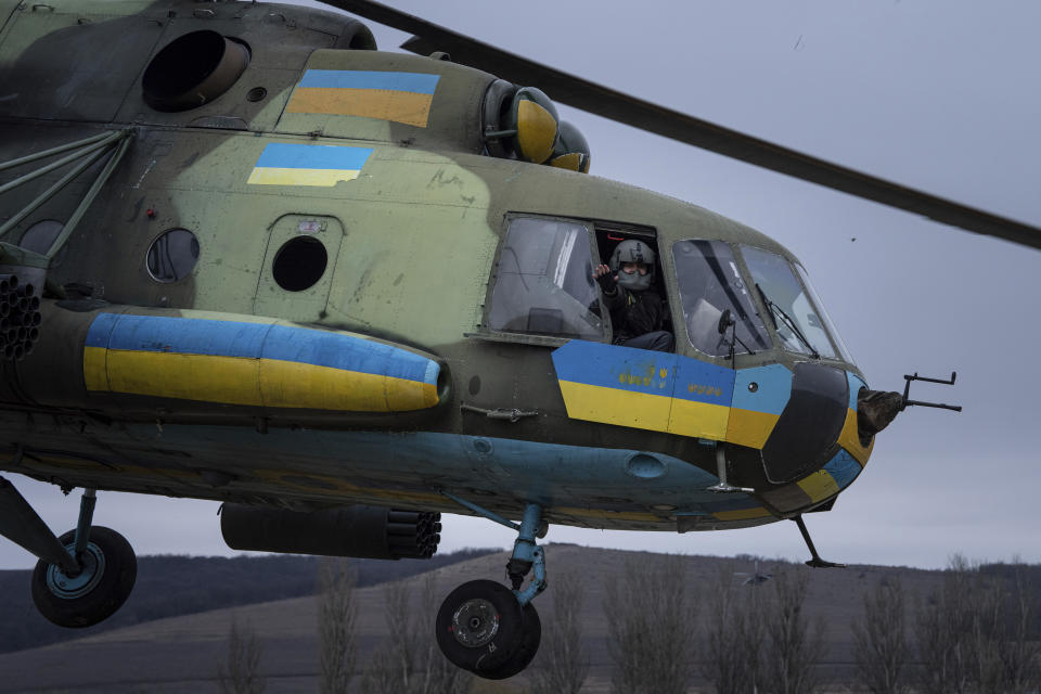Un piloto ucraniano saluda a sus camaradas desde un helicóptero de combate Mi-8 durante una misión de combate, el sábado 18 de marzo de 2023, en la región de Donetsk, Ucrania. (AP Foto/Evgeniy Maloletka)