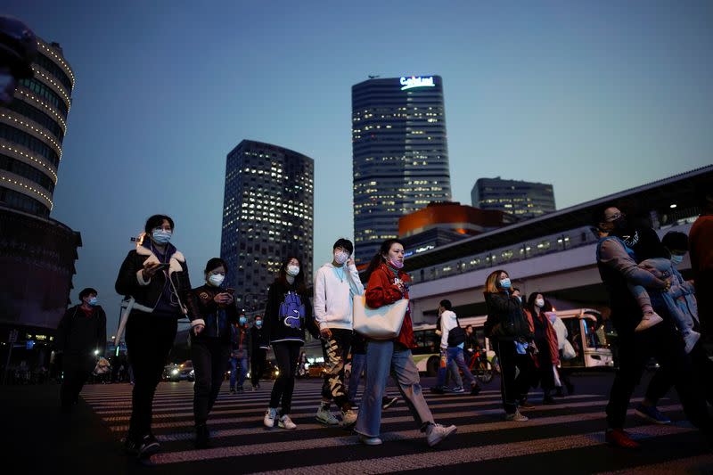 People wearing protective face masks are seen on a crossroad following the outbreak of coronavirus disease (COVID-19), in downtown Shanghai