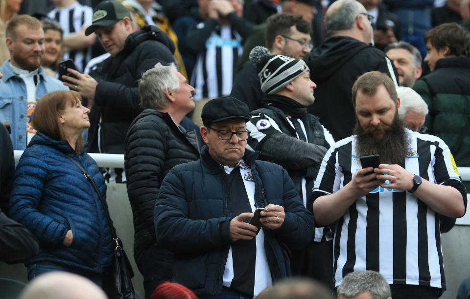 Fans check theor phones as an 'Emergency Alert' is sent to smart phone owners in the UK, during the English Premier League football match between Newcastle United and Tottenham Hotspur at St James' Park in Newcastle-upon-Tyne, north east England on April 23, 2023. - The UK conducted its first test of a new emergency alert service on Sunday, with millions of mobile phones emitting a loud alarm and vibration at 3:00pm (1400 GMT). (Photo by Lindsey Parnaby / AFP) / RESTRICTED TO EDITORIAL USE. No use with unauthorized audio, video, data, fixture lists, club/league logos or 'live' services. Online in-match use limited to 120 images. An additional 40 images may be used in extra time. No video emulation. Social media in-match use limited to 120 images. An additional 40 images may be used in extra time. No use in betting publications, games or single club/league/player publications. /  (Photo by LINDSEY PARNABY/AFP via Getty Images)