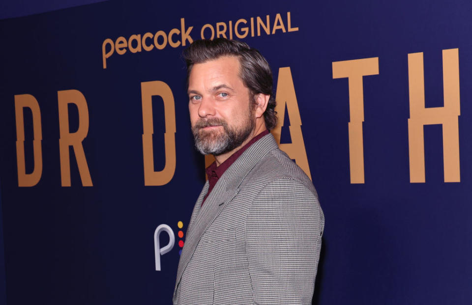 On the red carpet with a salt-and-pepper beard and mustache and in a suit