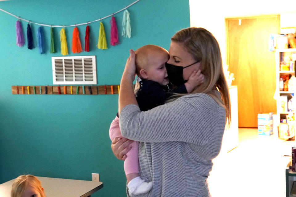 Amy McCoy cuddles a seven-month old baby at her Forever Young Daycare facility, Monday, Oct. 25, 2021, in Mountlake Terrace, Wash. Child care centers once operated under the promise that it would always be there when parents have to work. Now, each teacher resignation, coronavirus exposure, and day care center closure reveals an industry on the brink, with wide-reaching implications for an entire economy's workforce. (AP Photo/Elaine Thompson)