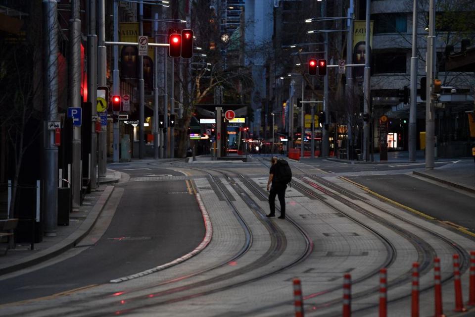 A man wearing a face mask walks along the quiet George Street in the central business district of Sydney.