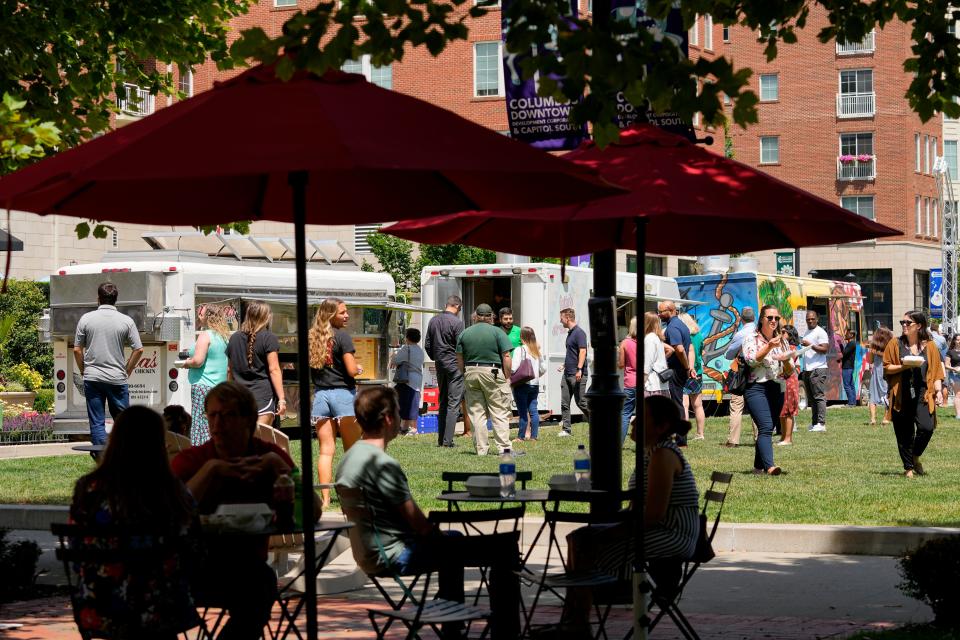 Diners relax and enjoy eating in the shade at the Columbus Commons' food truck food court.