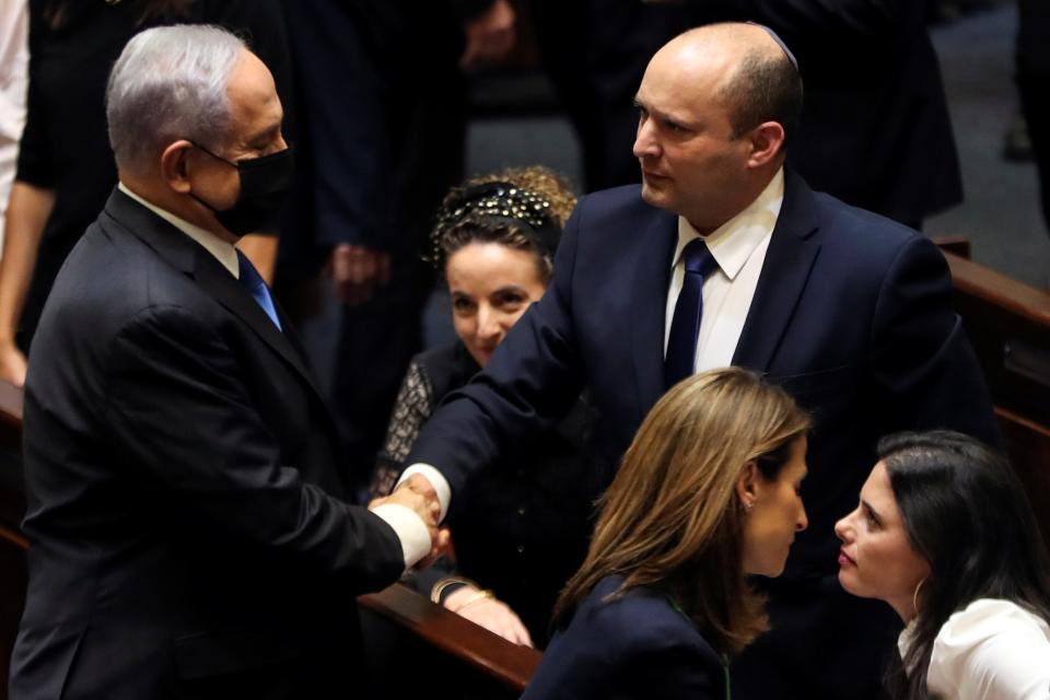 Benjamin Netanyahu shakes hands with the man who has replaced him as Israel Prime Minister, Naftali Bennett, following the vote on the new coalition at the Knesset, Israel’s parliament (REUTERS)