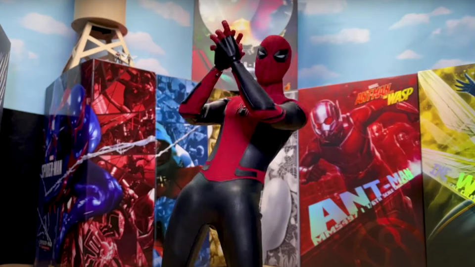 A stop-motion Spider-Man clapping his hands in front of a bunch of Marvel movie posters.