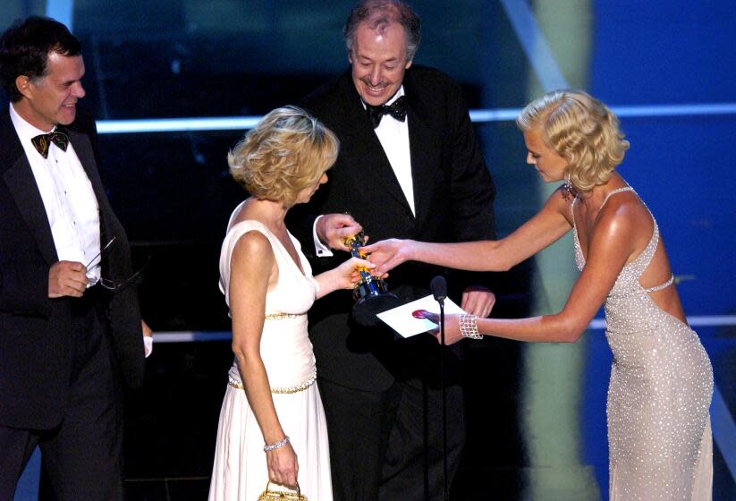 Winners for Best Foreign Language Film for "Barbarian Invasions" accept their award from Charlize Theron (Photo by M. Caulfield/WireImage)