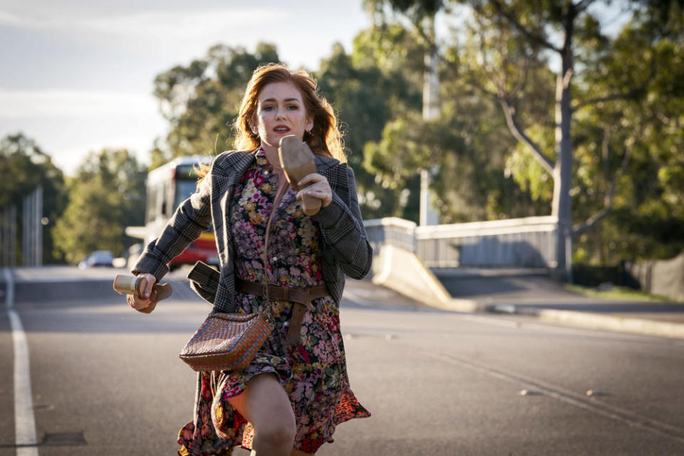 Isla Fisher running down the street with her shoes in her hands