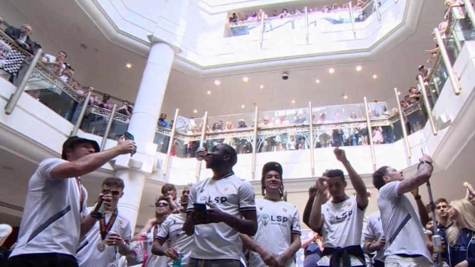 Players dance and film on their phones as crowds chant from the balconies of The Glades shopping centre