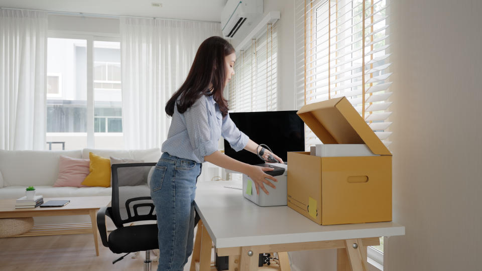 A woman arranging boxes on a desk.