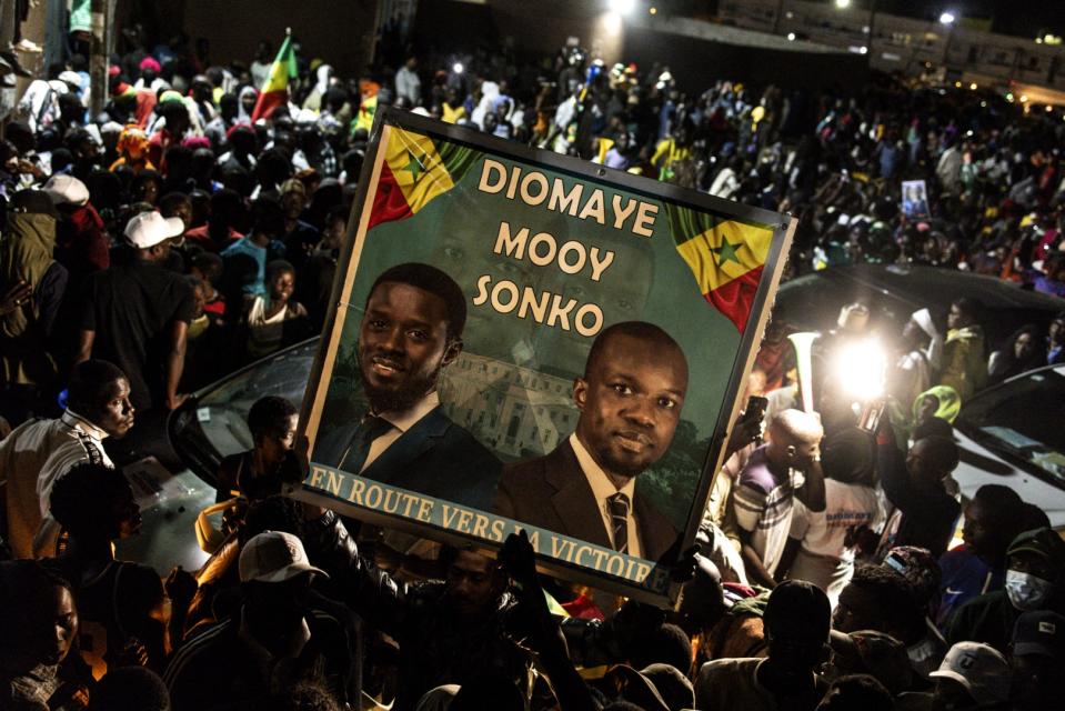 <span>Un partisan du candidat présidentiel Bassirou Diomaye Faye et du leader de l'opposition Ousmane Sonko brandit une affiche lors de leur dernier meeting de campagne au stade Caroline Faye de Mbour, le 22 mars 2024.</span><div><span>JOHN WESSELS</span><span>AFP</span></div>