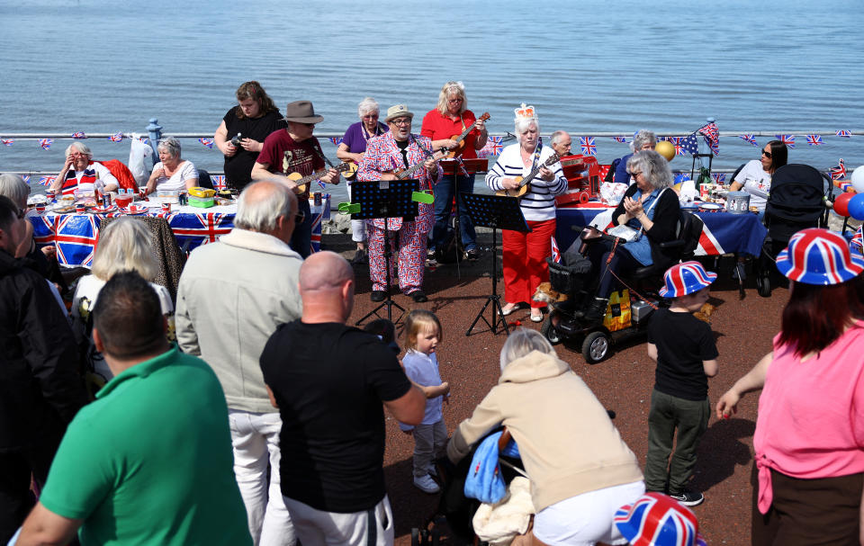 People watch Morecambe Ukulele Club play some music during celebrations for the Big Lunch on the prom, in Morecambe, Britain, May 7, 2023. REUTERS/Molly Darlington