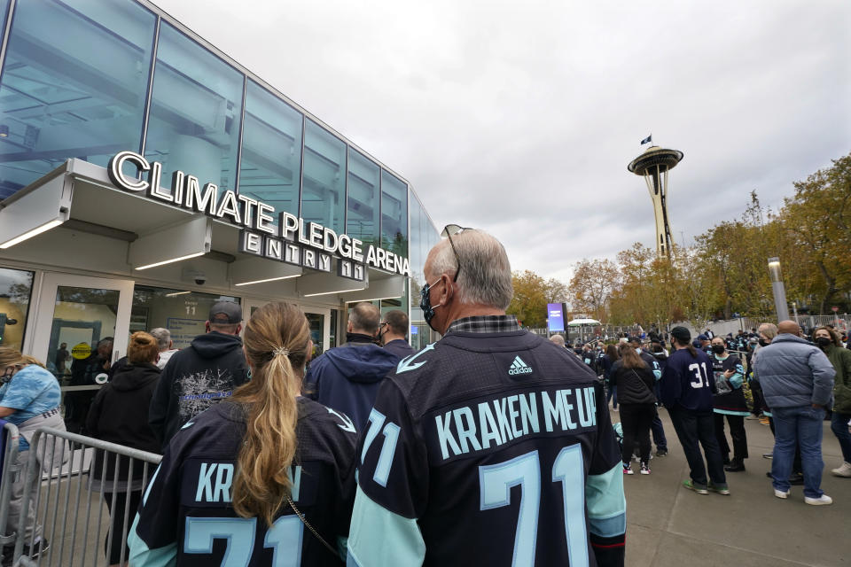 A Seattle Kraken hockey team flag flies atop the Space Needle, background, as fans wait to enter Climate Pledge Arena on Saturday, Oct. 23, 2021, in Seattle. The team was set to play its inaugural home match as the newest NHL team against the Vancouver Canucks later Saturday. (AP Photo/Elaine Thompson)