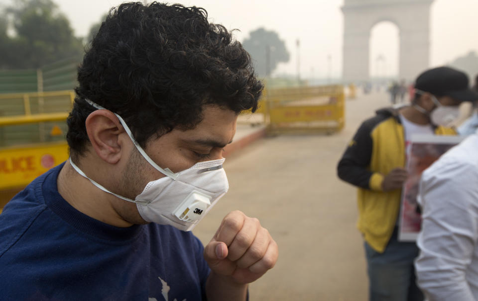 An Indian coughs even after wearing a mask a day after Diwali festival, in New Delhi, India, Thursday, Nov. 8, 2018. Toxic smog shrouds the Indian capital as air quality falls to hazardous levels with tens of thousands of people setting off massive firecrackers to celebrate the major Hindu festival of Diwali on Wednesday night. (AP Photo/Manish Swarup)