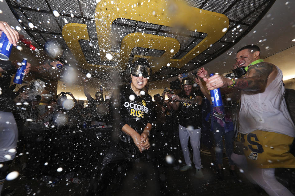 San Diego Padres' Leo Bae, center, dances with Manny Machado in the clubhouse following a baseball game against the Chicago White Sox after clinching a wild-card playoff spot Sunday, Oct. 2, 2022, in San Diego. (AP Photo/Derrick Tuskan)