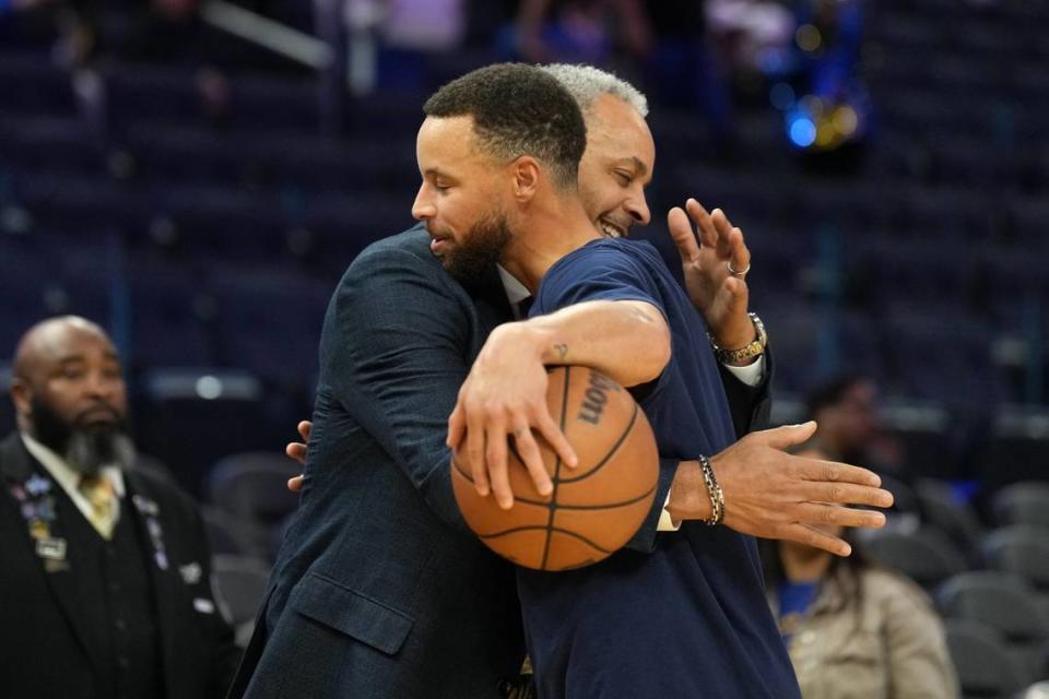 Charlotte Hornets color commentator Dell Curry (left) and Golden State Warriors guard Stephen Curry (right) hug before the game at Chase Center.