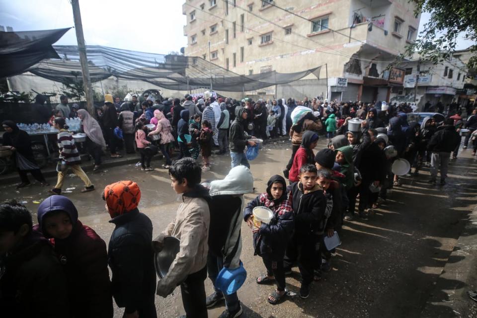 Displaced Palestinian children wait to collect food at a donation point in a refugee camp in Deir al-Balah, central Gaza.