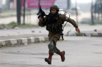 An Israeli soldier runs toward Palestinian demonstrators during clashes near Nablus, in the occupied West Bank February 23, 2018. REUTERS/Mohamad Torokman