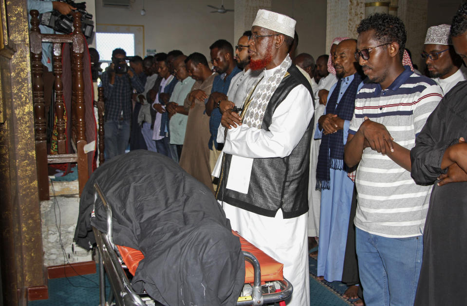 Mourners pray over the body of Somali Canadian peace activist Almaas Elman at her funeral service in the capital Mogadishu, Somalia Friday, Nov. 22, 2019. Preliminary investigations show Almaas Elman was killed by a stray bullet inside a heavily defended base near the international airport earlier this week in Mogadishu, the peacekeeping mission in Somalia said Friday. (AP Photo/Farah Abdi Warsameh)