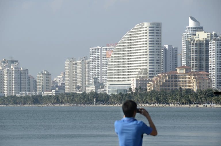 A man takes photos of buildings in the seaside city of Sanya, in China's southern Hainan province, on January 19, 2013. Chinese who cannot afford to buy a home have been frustrated by high housing costs for years