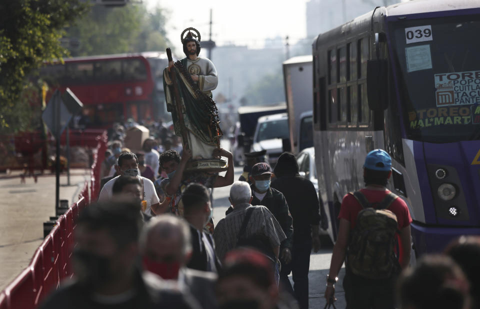 Faithful wearing protective face masks amid the new coronavirus, arrive to the San Hipolito Catholic church as part of the annual pilgrimage honoring Saint Jude, the patron saint of lost causes, in Mexico City, Wednesday, Oct. 28, 2020. Thousands of Mexicans did not miss this year to mark St. Jude's feast day, but the pandemic caused Masses to be canceled and the rivers of people of other years were replaced by orderly lines of masked worshipers waiting their turn for a blessing. (AP Photo/Marco Ugarte)