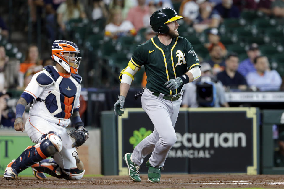Oakland Athletics designated hitter Jed Lowrie, right, watches his hit for a single in front of Houston Astros catcher Martin Maldonado, left, during the third inning of a baseball game Thursday, July 8, 2021, in Houston. (AP Photo/Michael Wyke)