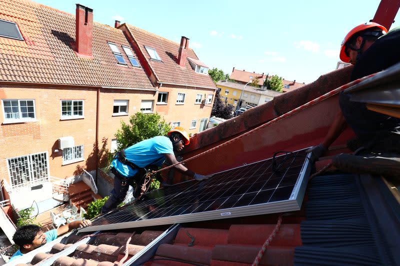 Kauahou, Navarro and Pascual, workers of the installation company Alromar, set up solar panels on the roof of a home in Colmenar Viejo