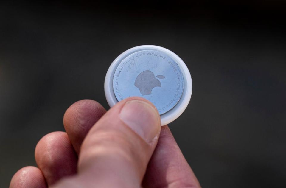 A person holds an Apple AirTag tracking device.