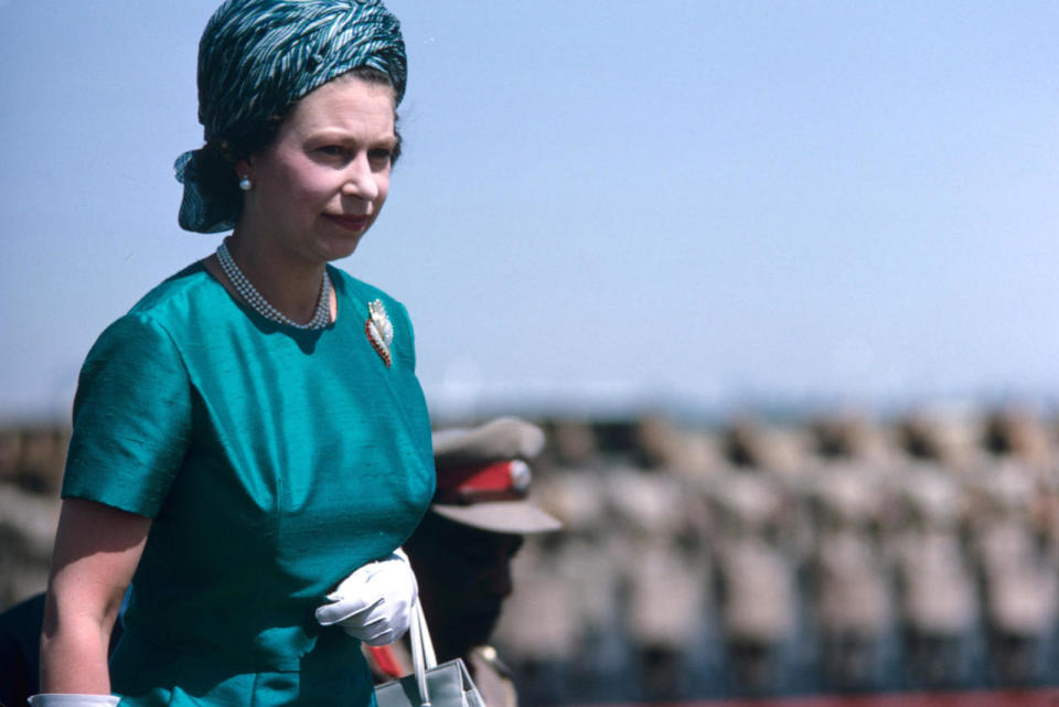 <p>Rocking a silk wrap headscarf like a pro, the Queen wears a lot of her other trademark accessories in this snapshot - including white gloves, pearls, a brooch and handbag. <i>[Photo: Rex]</i><br></p>