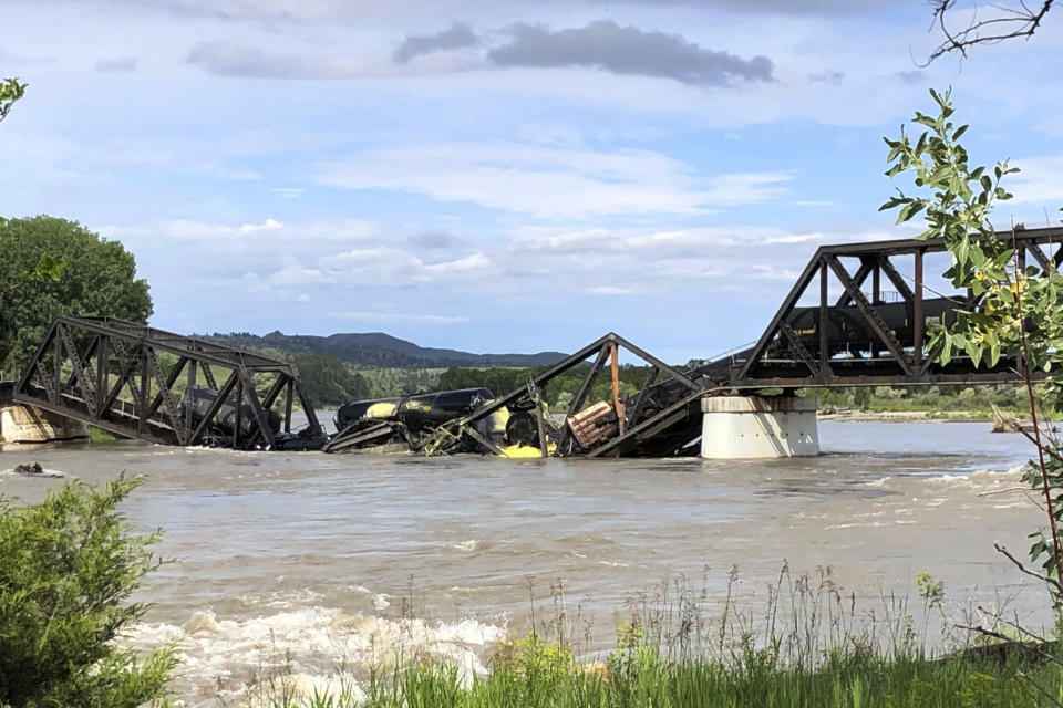 Several train cars are immersed in the Yellowstone River after a bridge collapse near Columbus, Mont., on Saturday, June 24, 2023. The bridge collapsed overnight, causing a train that was traveling over it to plunge into the water below. Authorities on Sunday were testing the water quality along a stretch of the Yellowstone River where mangled cars carrying hazardous materials remained after crashing into the waterway following a bridge collapse. (AP Photo/Matthew Brown)